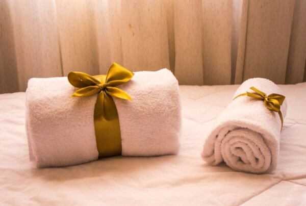 Luxurious white towels adorned with golden ribbons on a bed, creating an elegant and welcoming atmosphere.