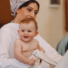 pexels-photo-17942940-17942940 Adorable baby held by a mother during a baptism ceremony in a church setting.