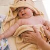pexels-photo-4668938-4668938 Cute newborn baby wrapped in a soft towel, smiling and feeling cozy indoors.