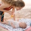 pexels-photo-5791413-5791413 A joyful mother enjoys a sunny day at the beach interacting with her baby, creating warm family memories.
