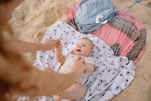 pexels-photo-5791414-5791414 A joyful baby on the beach with parent, enjoying playtime on a sunny day.