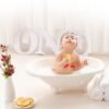 Cute Asian toddler in swimwear sitting in foamy water in bathtub and playing with soap bubbles