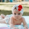 Cute baby in a floral turban lying on a blanket outdoors.