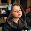Adorable child in a cozy hooded robe, enjoying a meal at home.
